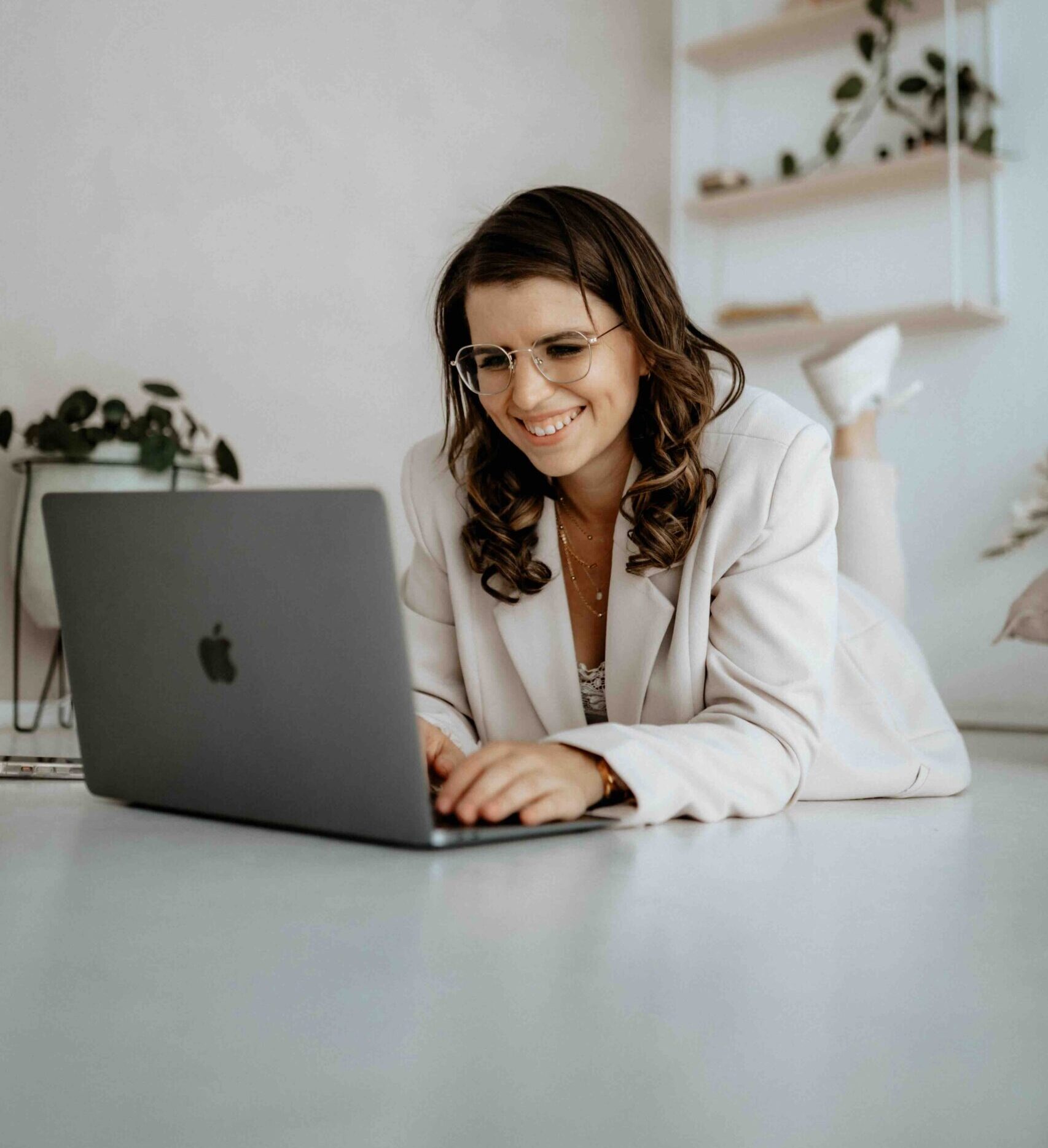 Lara, Gründerin von mondscheindesign, liegend auf dem Boden mit ihrem Laptop