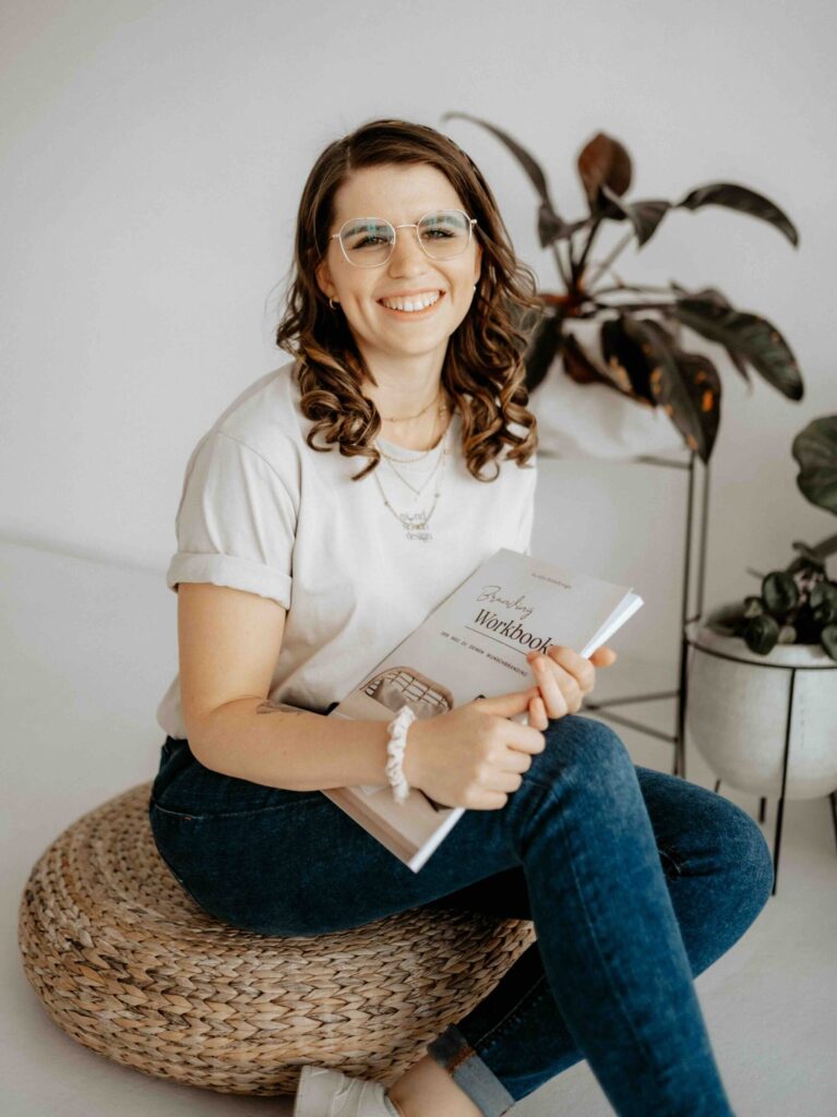 Lara, Gründerin von mondscheindesign, sitzend mit ihrem Workbook in der Hand